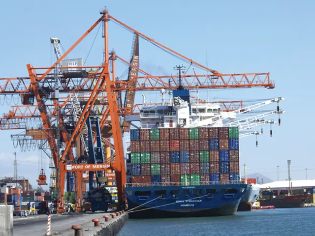 The image is taken from the port beside a sea,there are very big cranes and many goods on the...
