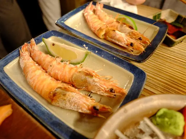 In the image we can see there are prawns and piece of lime kept in the plates. There is a soya...