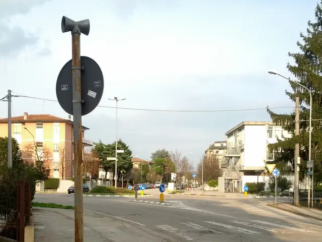 In this picture we can see a 4 way street surrounded with houses, trees and poles.