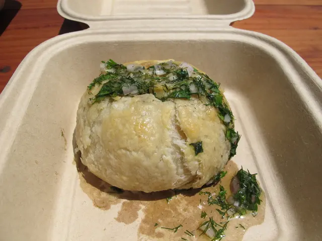 There is soup having leaf´s pieces and onions pieces poured on a food item in a white color box....